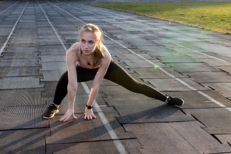 Female athlete preparing legs for cardio workout. Fitness runner doing warm-up routine. woman runner...