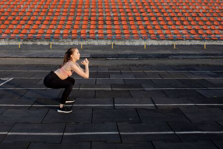 Female athlete preparing legs for cardio workout. Fitness runner doing warm-up routine. woman runner warm up outdoor. athlete stretching and warming up on a running track in a stadium.の写真素材
