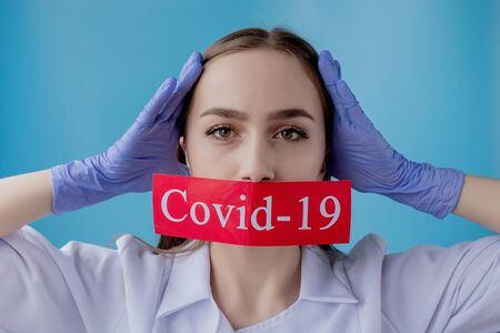 Doctor woman pointing to red paper with mesaage Coronavirus on blue background. World Health Organization WHO introduced new official name for Coronavirus disease named COVID-19.の写真素材