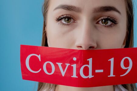 Doctor woman pointing to red paper with mesaage Coronavirus on blue background. World Health Organization WHO introduced new official name for Coronavirus disease named COVID-19.の写真素材