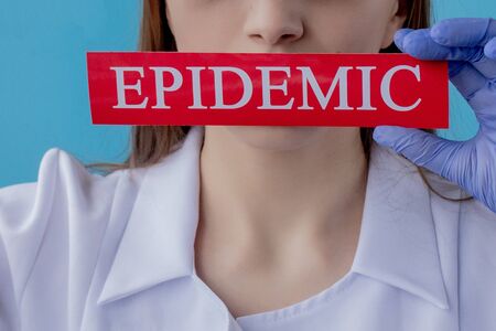 Doctor woman pointing to red paper with mesaage Coronavirus on blue background. World Health Organization WHO introduced new official name for Coronavirus disease named COVID-19.の写真素材