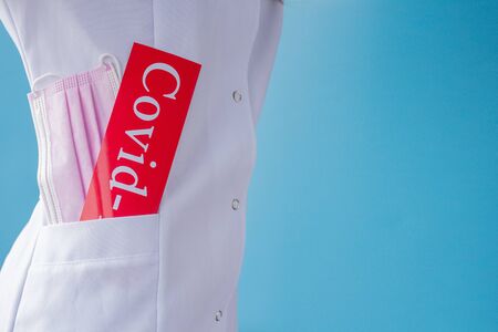 medical mask and inscription COVID-19 in Doctor's Pocket.の写真素材