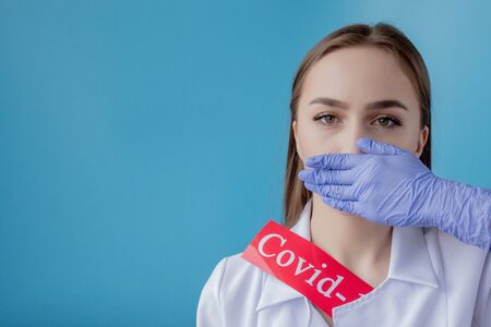 Doctor woman pointing to red paper with mesaage Coronavirus on blue background. World Health Organization WHO introduced new official name for Coronavirus disease named COVID-19.の写真素材
