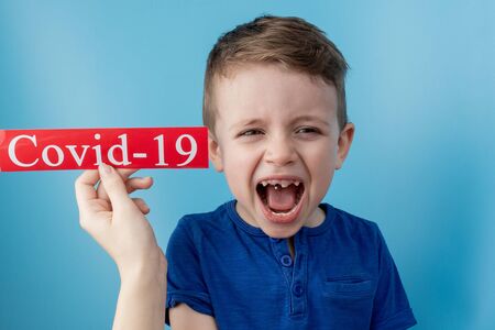 Little boy pointing to red paper with mesaage Coronavirus on blue background. World Health Organization WHO introduced new official name for Coronavirus disease named COVID-19.の写真素材