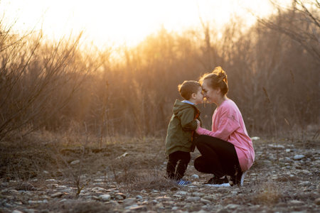 Beautiful mother playing with her son in nature against sunset. Mother's day concept.