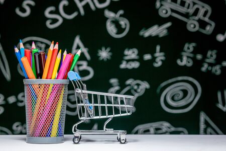 Back to school background with books, pencils and globe on white table on a green blackboard backgroundの写真素材