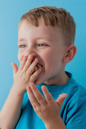 Little Boy Holding and eating an Banana on blue background, food, diet and healthy eating concept.