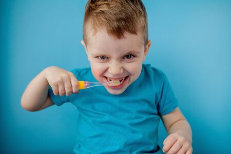 Little cute boy brushing his teeth on blue background.の写真素材