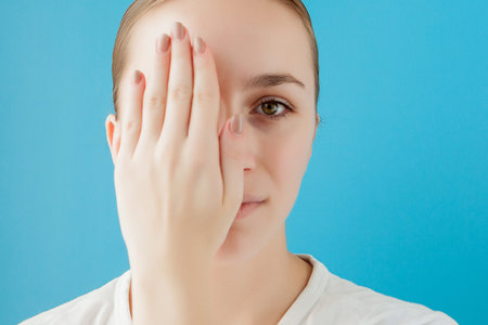 Portrait of joyful girl covering her eye by a cream can. She is looking at camera and laughingの写真素材