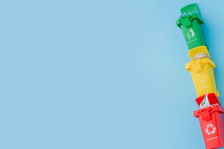 Yellow, green and red recycle bins with recycle symbol on blue background. Keep city tidy, Leaves the recycling symbol. Nature protection concept.の写真素材