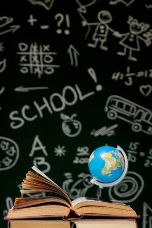Book stack on a green blackboard background, back to school concept.の写真素材