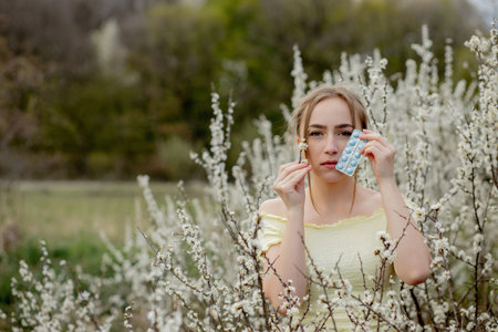 Woman with medicine in the hands Fighting Spring Allergies Outdoor - Portrait of an allergic woman surrounded by seasonal flowers.の写真素材