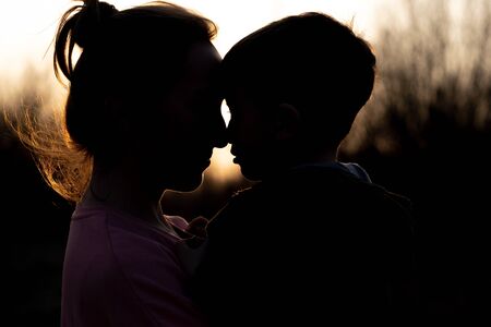 Silhouette of a mother and son playing outdoors at sunset. Mother's day concept.の写真素材