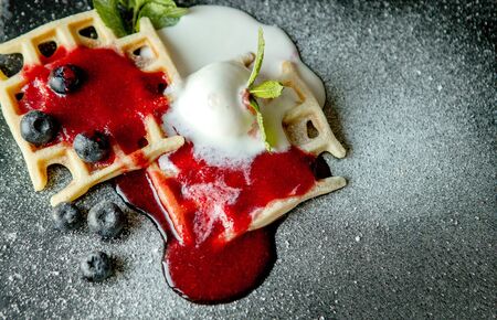 Fresh baked homemade classic Belgian waffles topped with icecream, fresh blueberries and mint, top down view. Savory waffles. Breakfast concept.の写真素材