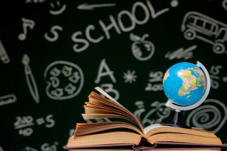 Book stack on a green blackboard background, back to school concept.の写真素材