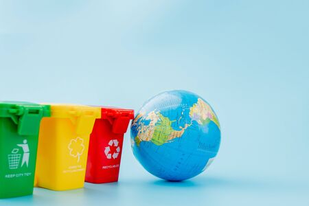 Yellow, green and red recycle bins with recycle symbol on blue background. Keep city tidy, Leaves the recycling symbol. Nature protection concept.の写真素材