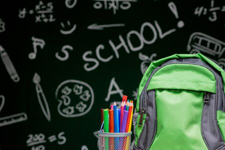 Education concept - green backpack, notebooks and school supplies on the background of the blackboard.の写真素材