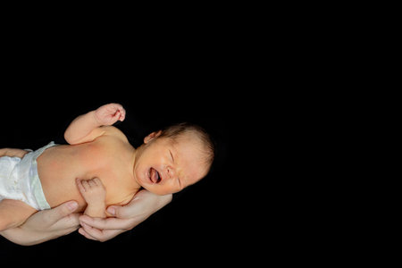 Father holding his 15 days old son in his hand on black background.の写真素材