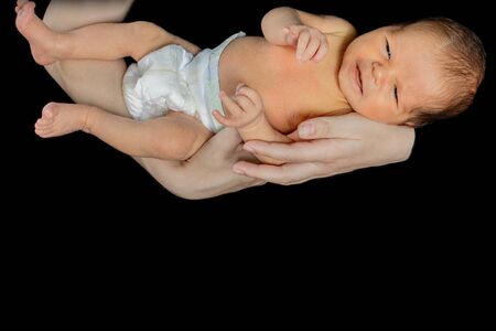 Father holding his 15 days old son in his hand on black background.の写真素材