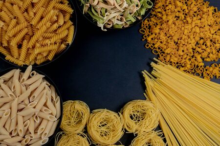 Assortment of different types of pasta dry on black backgroundの写真素材