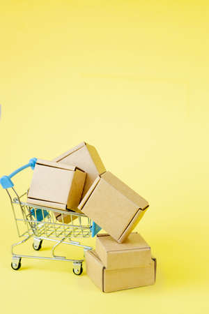 Paper shopping bags in a shopping cart on yellow background, concept online shoppingの写真素材