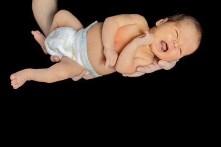 Father holding his 15 days old son in his hand on black background.の写真素材