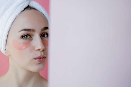Portrait of Beauty Woman with Eye Patches on pink background. Woman Beauty Face with Mask under Eyes. Skin care, cosmetic product concept with copy space.の写真素材
