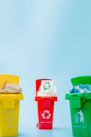 Yellow, green and red recycle bins with recycle symbol on blue background. Keep city tidy, Leaves the recycling symbol. Nature protection concept.の写真素材