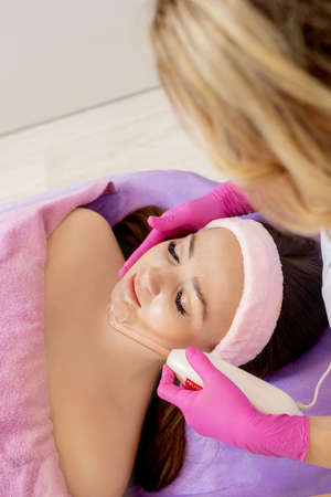 Darsonvalization of the face or rejuvenation of the face with the help of electrotherapy. Photo of darsonval for the face. Current therapy. The patient is at the beauticianの写真素材