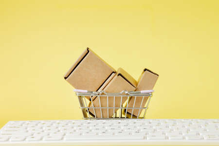 Online shopping concept. Shopping cart with small boxes inside on yellow background. Logistics and transportation management ideas and Industry business commercial conceptの写真素材