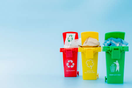 Yellow, green and red recycle bins with recycle symbol on blue background.の写真素材