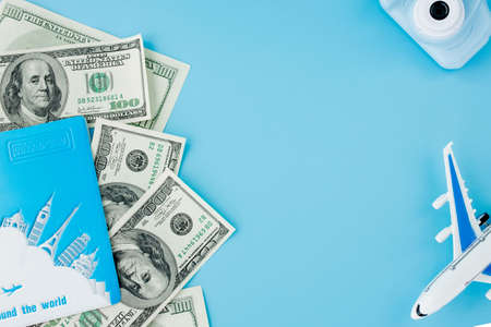 Passport with model of passenger plane and dollars on blue background. Travel concept, copy spaceの写真素材