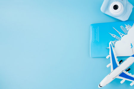 Camera, passport and airplane on light blue background.Summer or vacation concept. Copy space