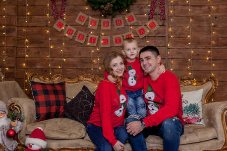 Christmas Family. Happiness. Portrait of dad, mom and sonsitting on a couch at home near the Christmas tree, all are smiling. The concept of family winter holidayの写真素材