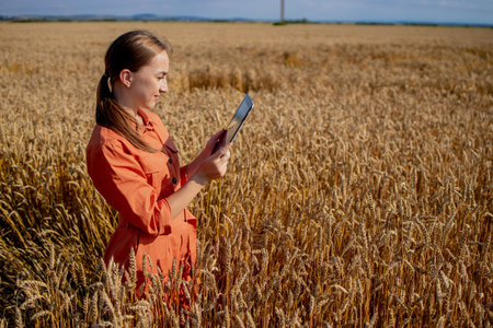 Woman caucasian technologist agronomist with tablet computer in the field of wheat checking quality...