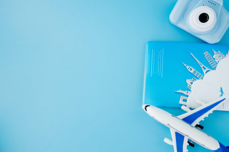 Camera, passport and airplane on light blue background.Summer or vacation concept.