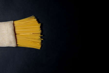 Dry spaghetti stands on a black background. Cooking concept. Space for textの写真素材