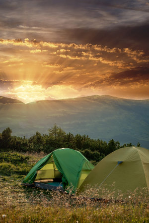 view of tourist tent in mountains at sunrise or sunset. Camping background. Adventure travel active...