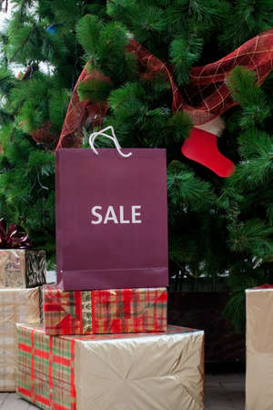 Christmas gift boxes and shopping package under Chrismas tree lies on white carpet near fireplace Holiday morning. New year present paper package. Festive mood.の写真素材