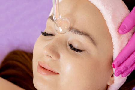 Darsonvalization of the face or rejuvenation of the face with the help of electrotherapy. Photo of darsonval for the face. Current therapy. The patient is at the beauticianの写真素材
