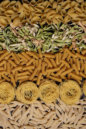 Variety of types and shapes of dry Italian pasta. Italian Macaroni raw food background or texture:pasta, spaghetti , pasta in shape of spiral.の写真素材