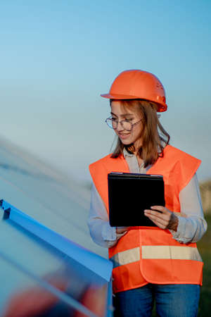 Inspector Engineer Woman Holding Digital Tablet Working in Solar Panels Power Farm, Photovoltaic Cell Park, Green Energy Concept.の写真素材
