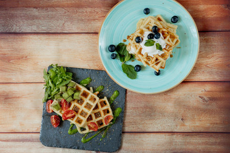 Fresh baked sweet and salty Belgian waffles on wooden background, top down view. Savory waffles....