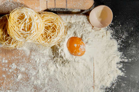 flat lay with rolling pin and ingredients for italian pasta arranged on black tabletop.の写真素材