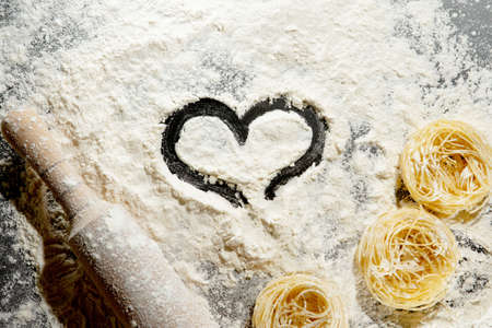 Heart of flour and rolling pin on black background. Top view, copy space.の写真素材