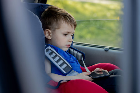 Portrait of a bored little boy sitting in a car seat. Safety of transportation of children