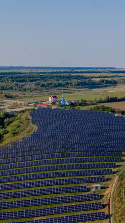 Aerial Top view on Solar Power Station in Green Field on Sunny day. Drone fly over Solar Farm. Lot of Solar Panels Stand in Row for Power Production. Renewable green energy.の写真素材