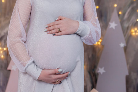 Pregnant woman holding baby booties. Belly with booties close up.
