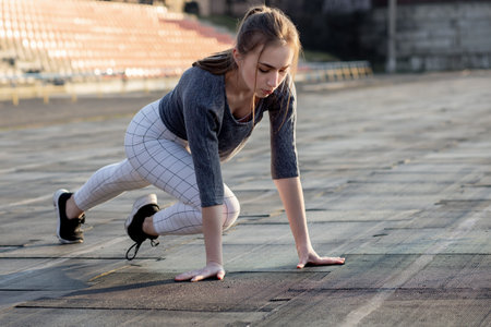 Female runner stretching legs on running track.