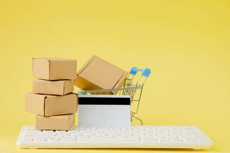 Online shopping concept. Shopping cart with small boxes inside on yellow background. Logistics and transportation management ideas and Industry business commercial conceptの写真素材